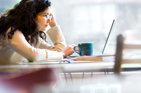 female working on a laptop computer with a coffee cup at the University of Illinois
