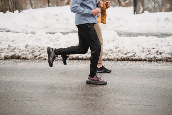 picture of two persons running on the road beside the snow