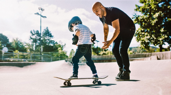 picture of a person beside a kid on a skateboard wearing skate protection