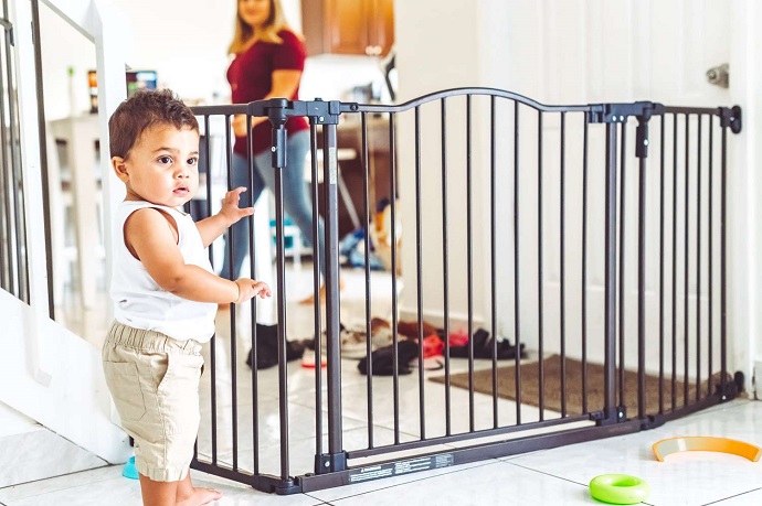 picture of a baby boy standing beside a safety gate in the living room